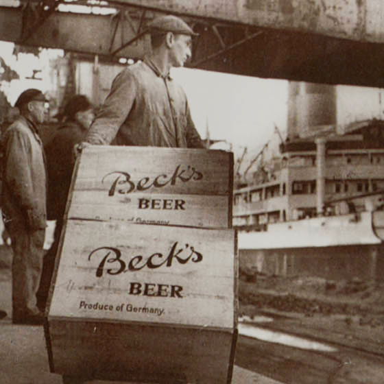 A man with two wooden boxes with the name 'BECK’S